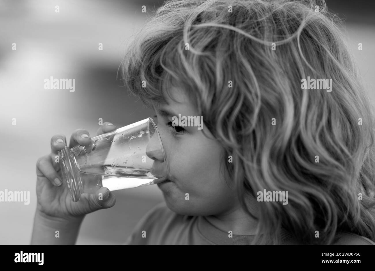 Portrait d'un garçon buvant un verre d'eau. Eau potable pour les enfants à l'extérieur. Enfant assoiffé. Banque D'Images