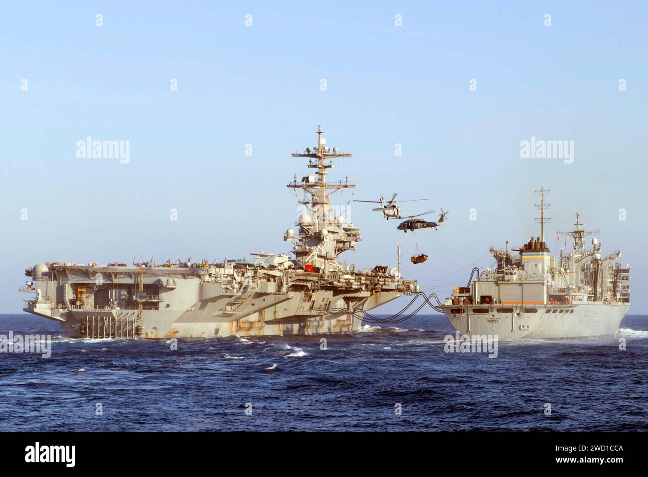 Deux hélicoptères MH-60S Sea Hawk transportent des fournitures de l'USNS Supply à l'USS George H.W. Bush. Banque D'Images