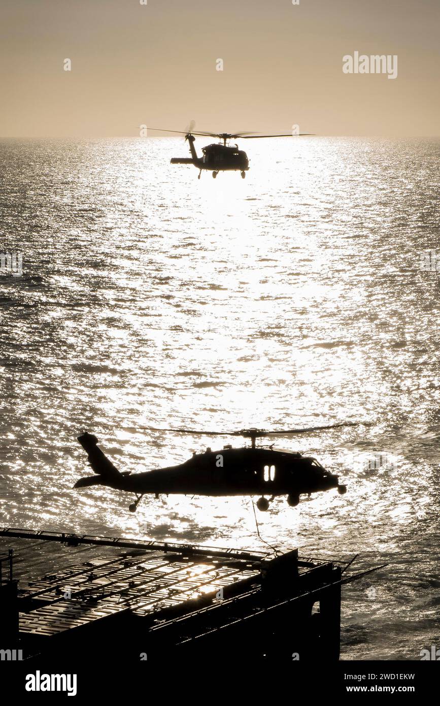 Deux hélicoptères MH-60S Sea Hawk transportent des munitions dans l'océan Pacifique. Banque D'Images