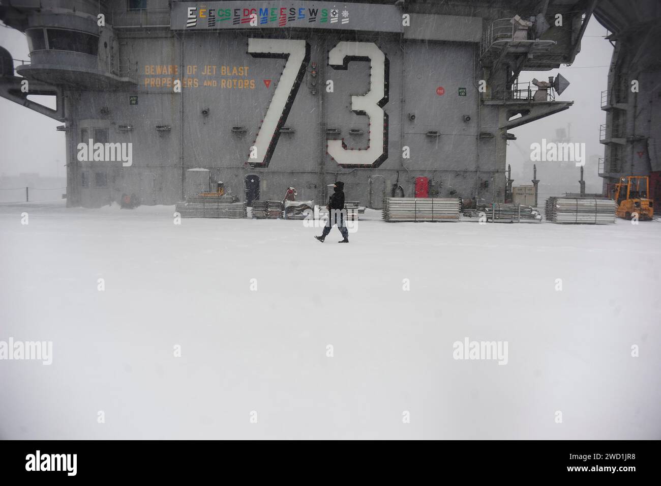 Airman effectue une rove de sécurité à bord du pont d'envol de l'USS George Washington pendant une tempête hivernale. Banque D'Images