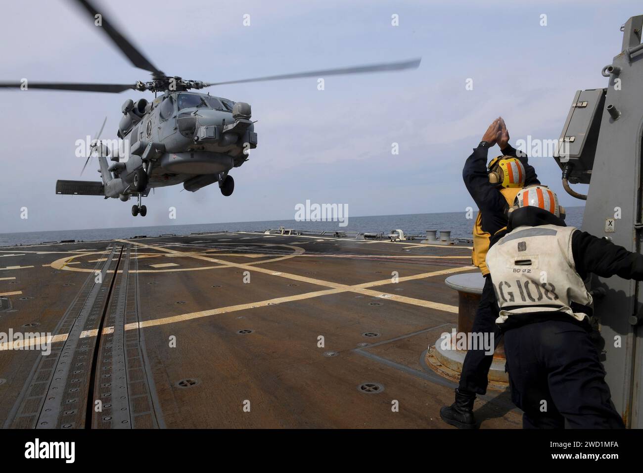 Boatswain's Mate signale à un MH-60R Sea Hawk sur le pont d'envol de l'USS Wayne E. Meyer. Banque D'Images