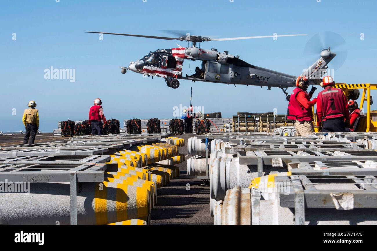 Les marins attachent une palette de munitions à un MH-60S Sea Hawk à bord de l'USS Makin Island. Banque D'Images