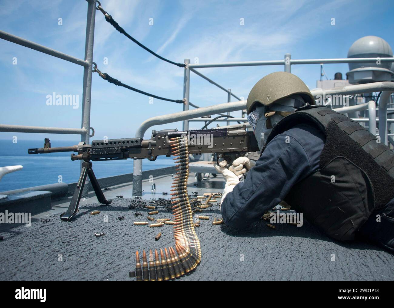 Fire Controlman tire une mitrailleuse M240B sur l'aile du pont tribord de l'USS Rushmore. Banque D'Images