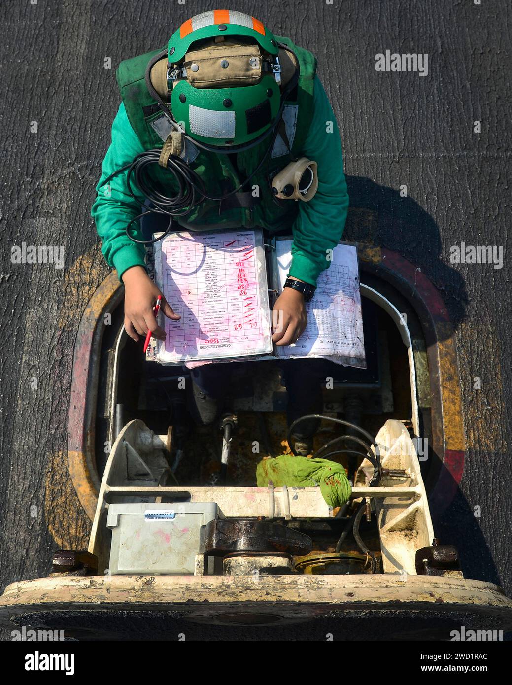 L'aviateur vérifie le journal de panne de la catapulte trois sur le pont d'envol de l'USS Nimitz. Banque D'Images