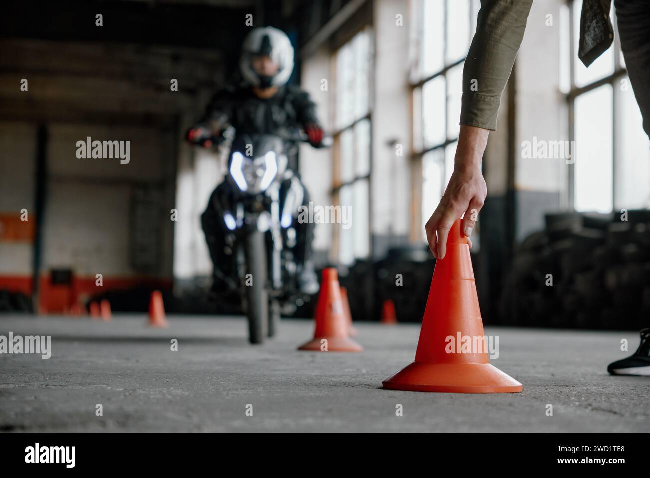 Leçon d'école de conduite de moto avec instructeur mettant le cône sur la piste Banque D'Images