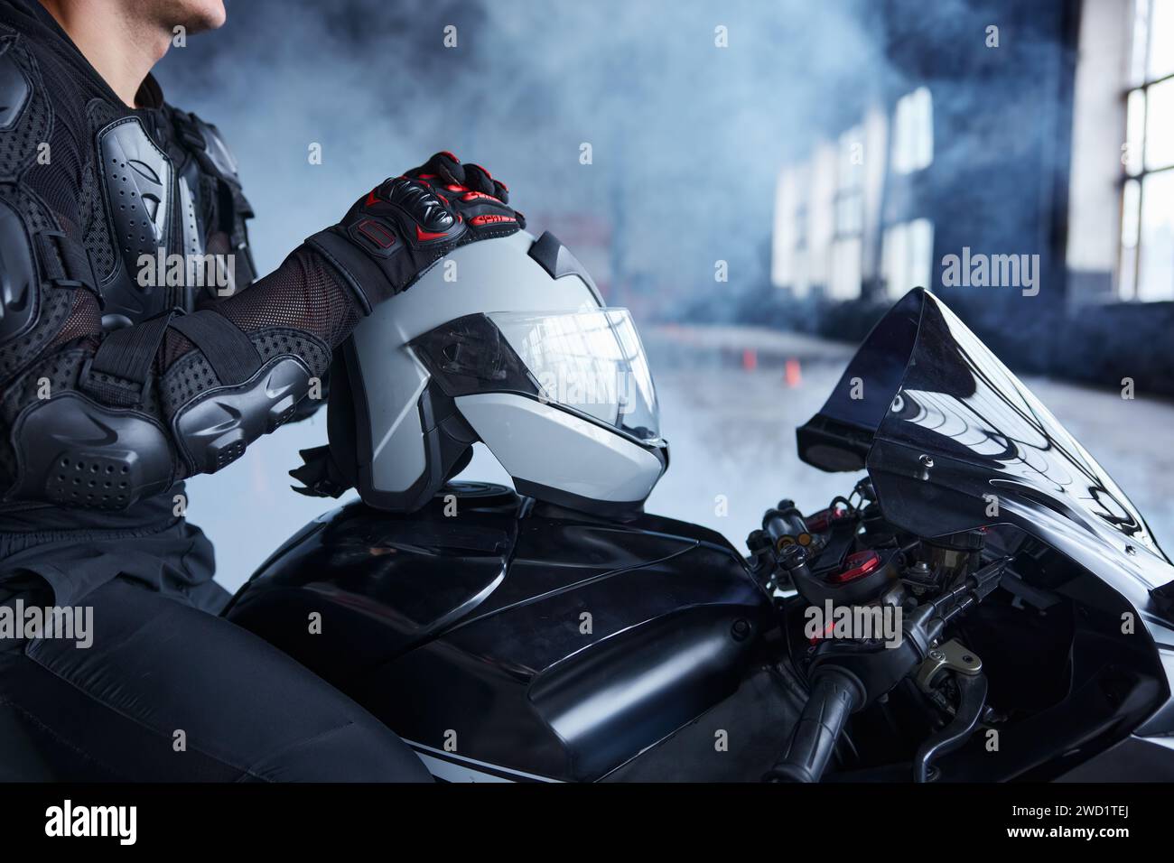Gros plan coupé motocycliste sur moto assis tenant un casque de protection Banque D'Images