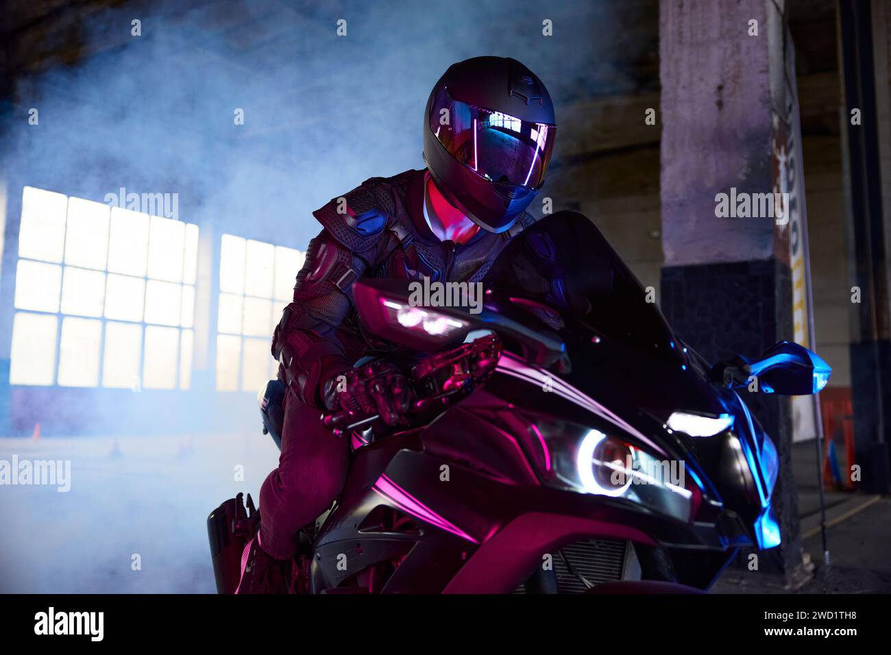 Portrait de motard conduisant la moto de sport dans la lumière de néon Banque D'Images