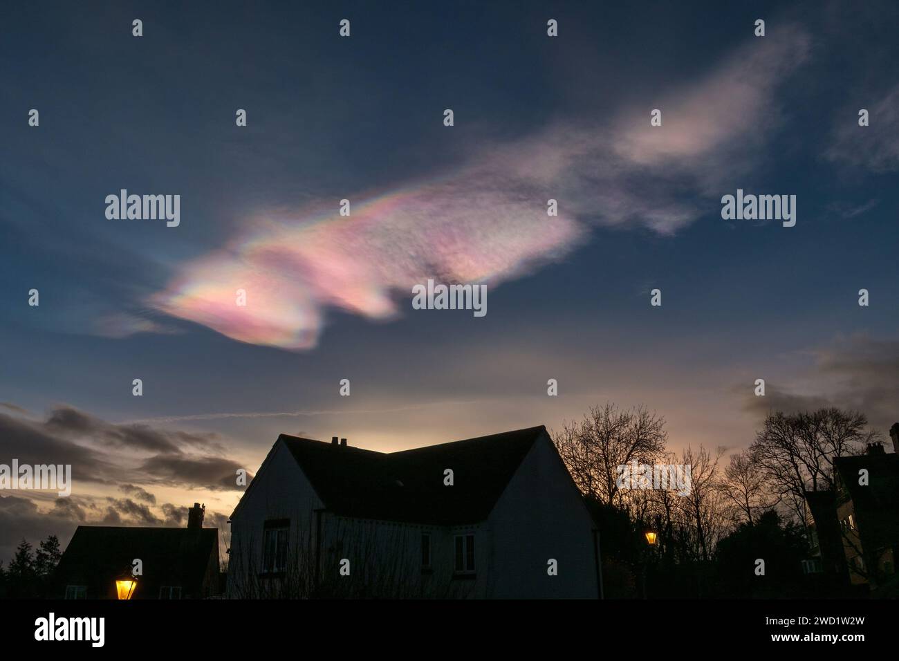 Rares, beaux et colorés nuages nacréens (nuages de nacre / nuages arc-en-ciel) dans le ciel du soir au-dessus des toits, Leicestershire, décembre 2023 Banque D'Images