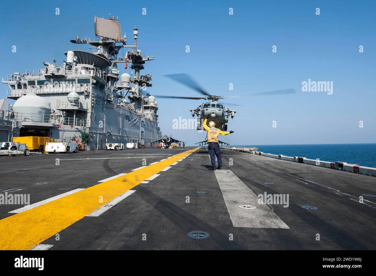 Aviation Boatswain's Mate signale à un hélicoptère MH-60S Sea Hawk de décoller de l'USS America. Banque D'Images