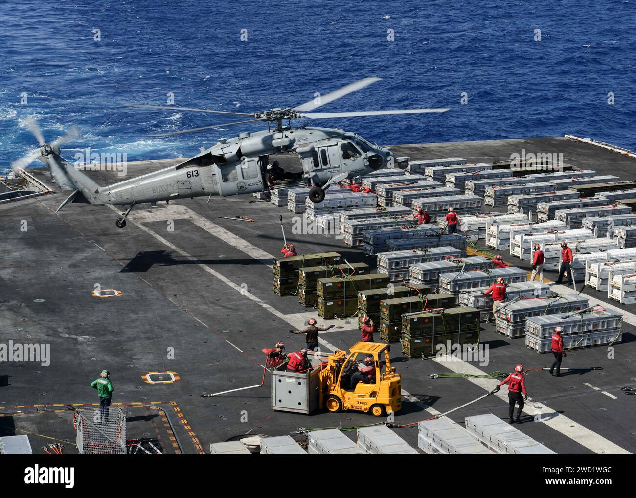Les marins se préparent à accrocher des munitions à un hélicoptère MH-60S Sea Hawk à bord de l'USS Nimitz. Banque D'Images