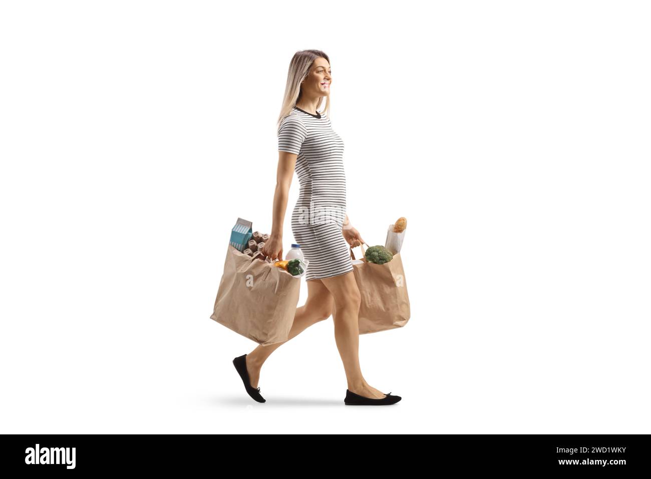 Plan complet d'une jeune femme marchant avec des sacs d'épicerie isolés sur fond blanc Banque D'Images