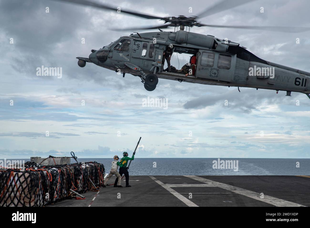 Les aviateurs attachent des fournitures à un hélicoptère MH-60S Sea Hawk lors d'un réapprovisionnement en mer. Banque D'Images
