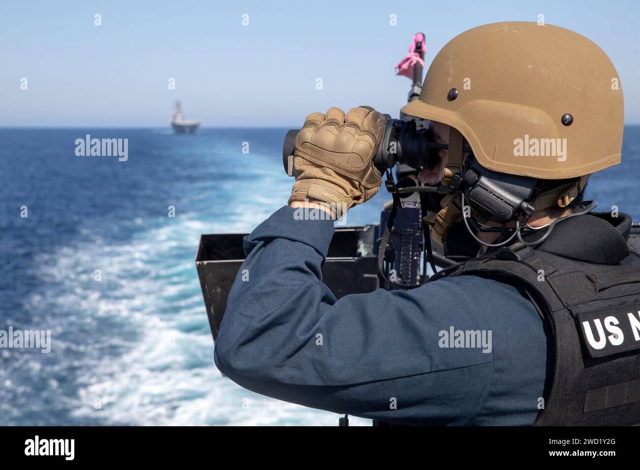 Gunner's Mate scanne l'océan Pacifique à la recherche de cibles avec des jumelles tout en assurant la sécurité. Banque D'Images