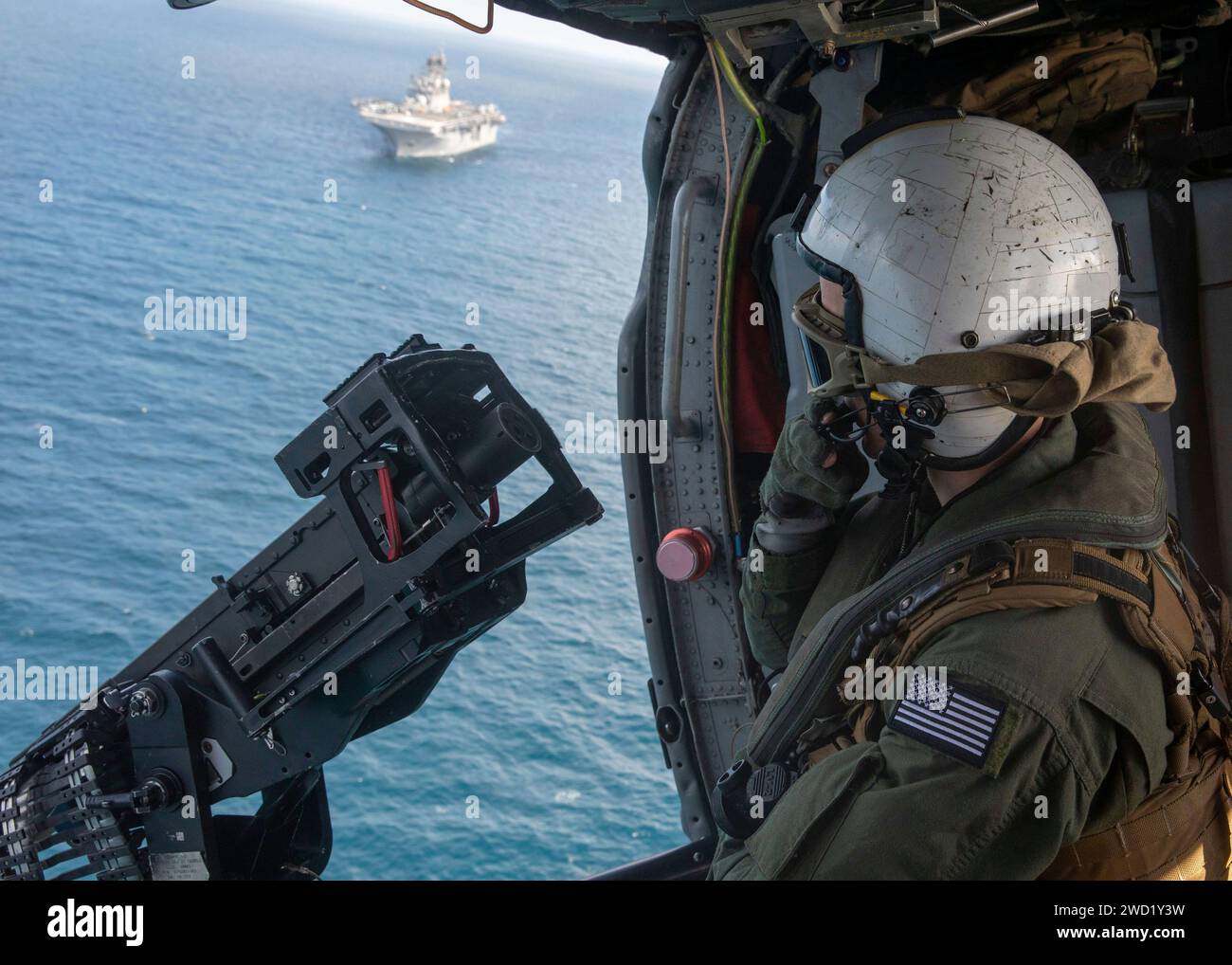 Naval Air Crewman utilise une mitrailleuse de calibre .50 dans un hélicoptère MH-60S Sea Hawk. Banque D'Images