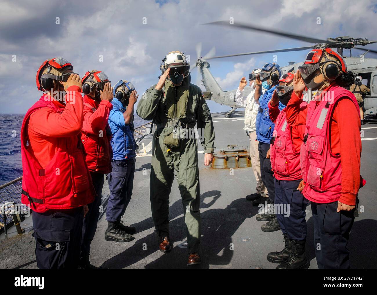 Le commandant salue les sideboys sur le pont d'envol alors qu'il monte à bord de l'USS John S. McCain. Banque D'Images
