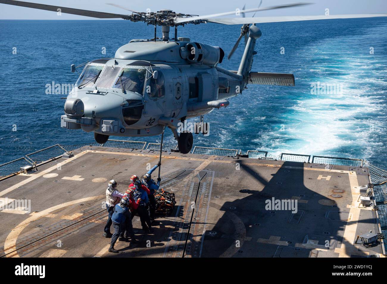 Les marins attachent un pendentif cargo à un hélicoptère MH-60R Sea Hawk sur le pont d'envol de l'USS Sterett. Banque D'Images