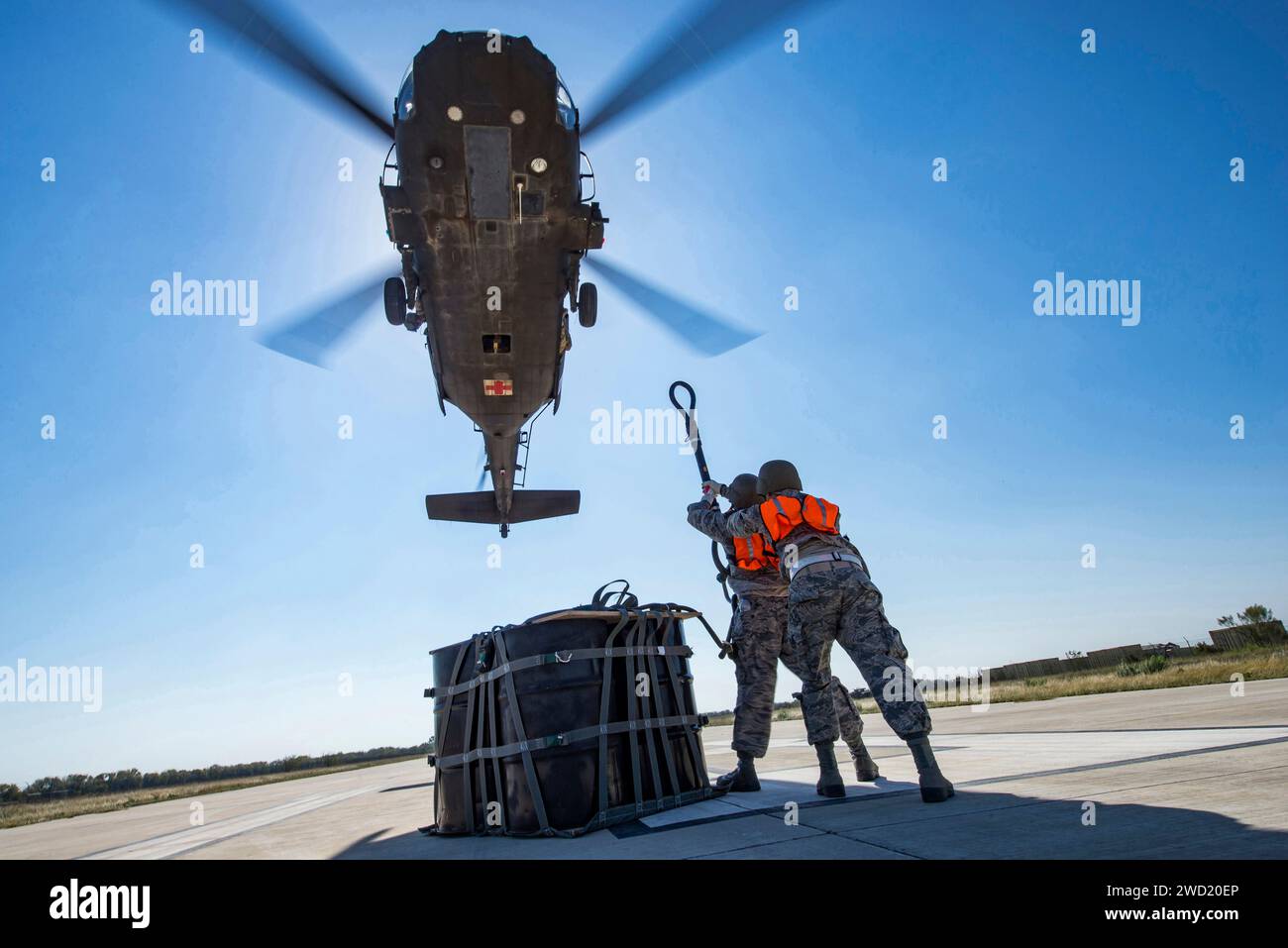 Les aviateurs attachent un sac cargo A-22 avec 2 000 livres de secours au crochet cargo d'un hélicoptère UH-60 Black Hawk. Banque D'Images