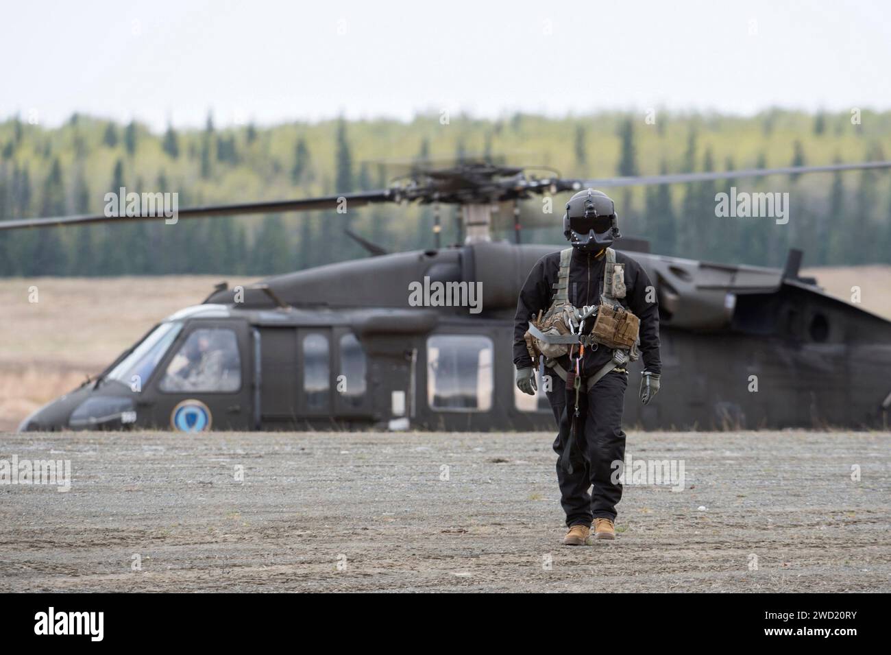 Un chef d'équipage d'hélicoptère UH-60 Black Hawk de l'armée américaine approche du personnel de champ. Banque D'Images