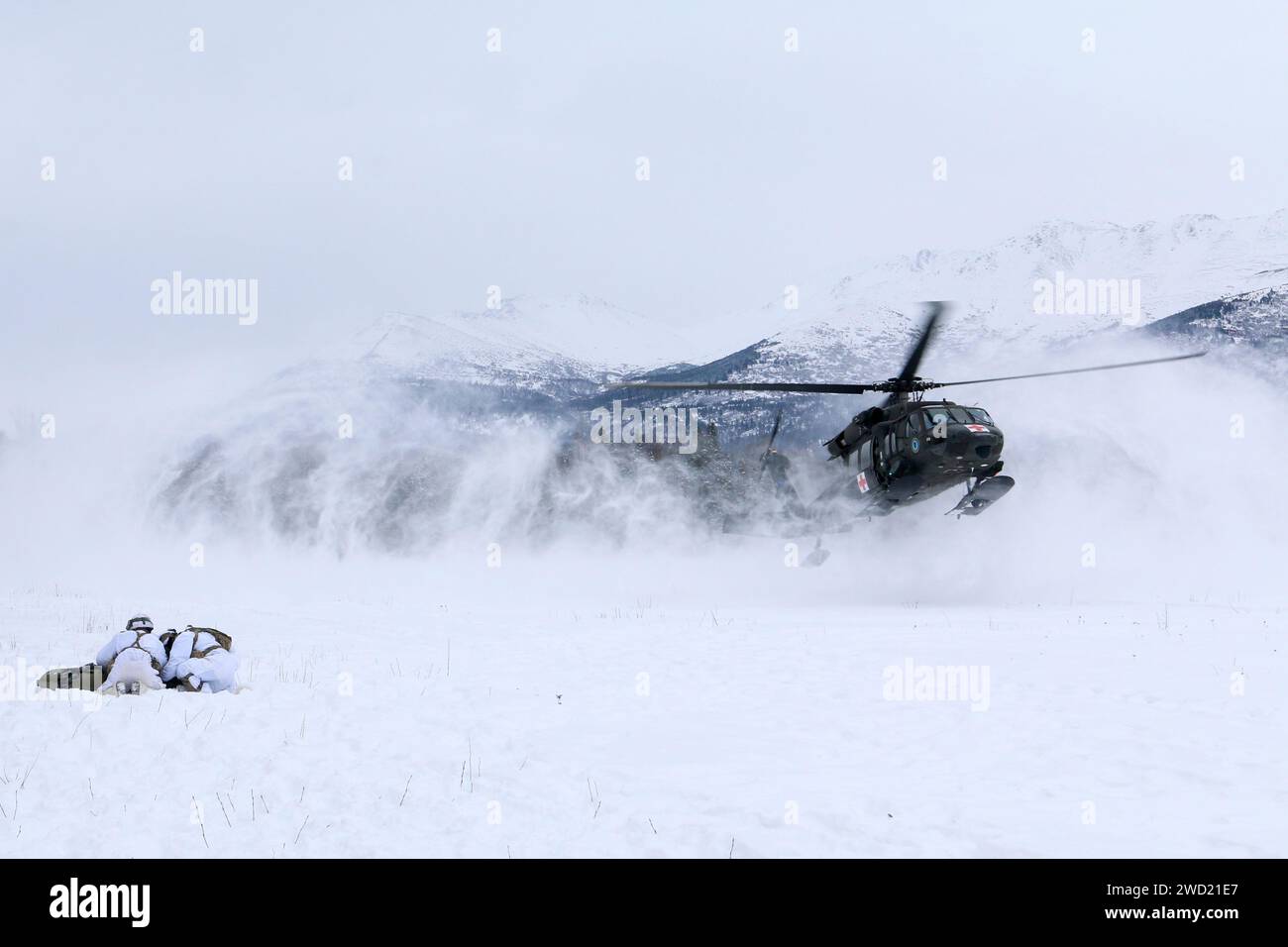 Les parachutistes se blottissent sur une fausse victime pour la protéger du lavage de rotor d'un hélicoptère UH-60 à l'atterrissage. Banque D'Images