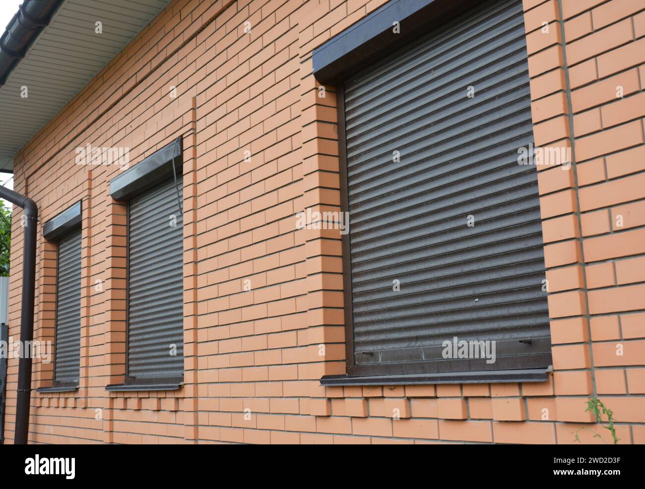 Les volets roulants abritent la protection des fenêtres. Maison en brique avec volets roulants sur les fenêtres Banque D'Images