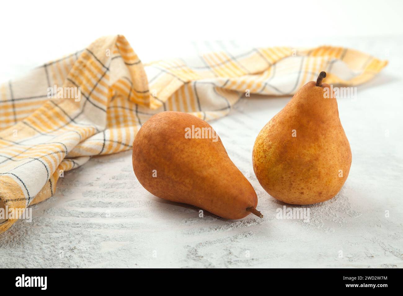 Plusieurs fruits de poire juteux mûrs et serviette de cuisine jaune sur fond en bois blanc. Banque D'Images