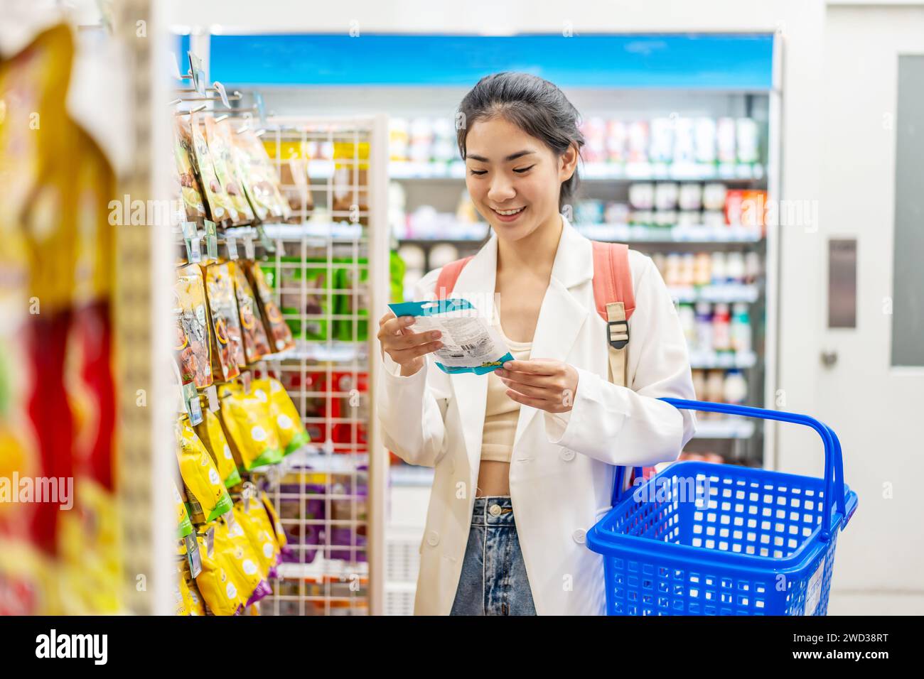 Excité jeune femme souriante magasinant près des étagères dans le supermarché Banque D'Images