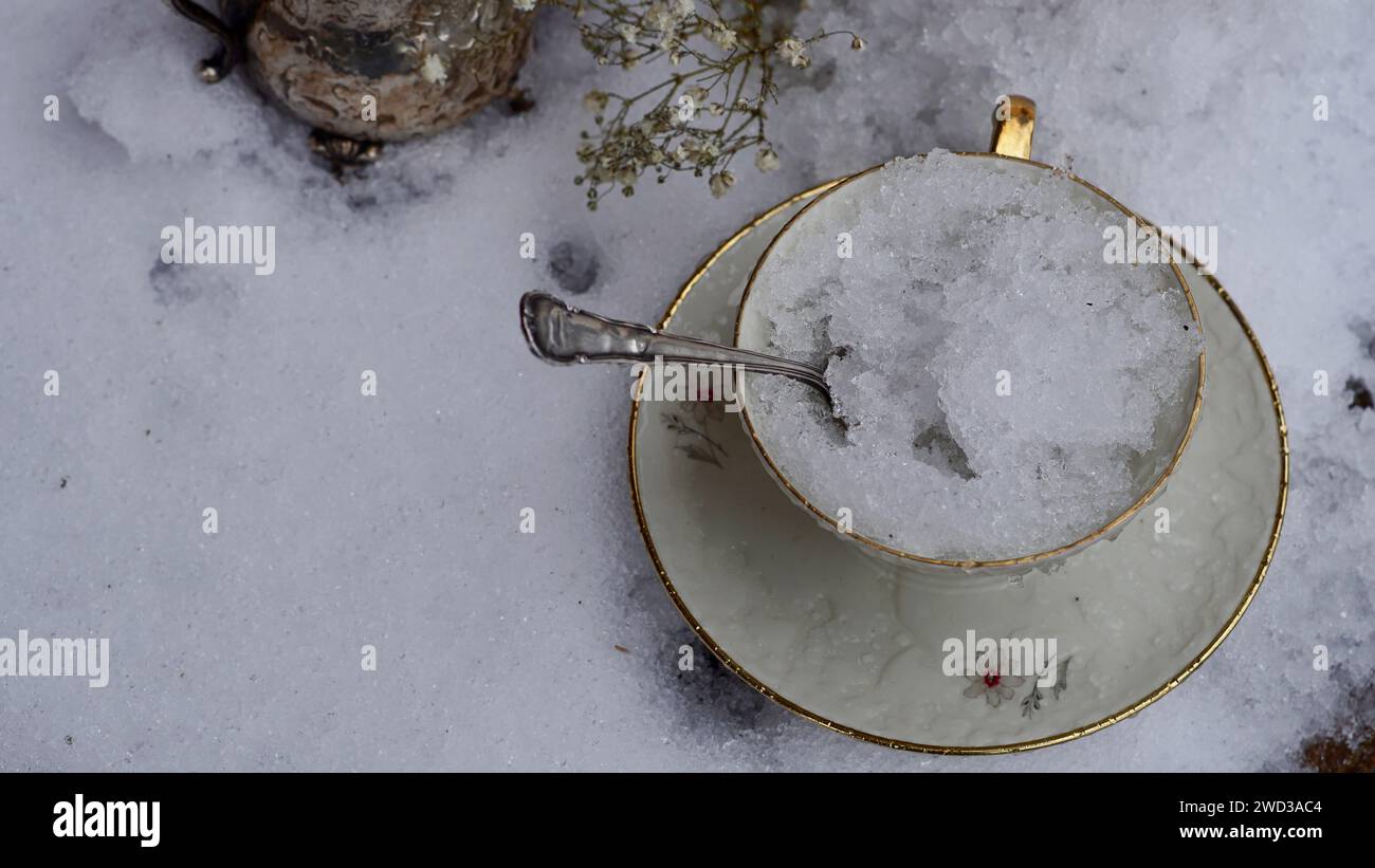 Une vieille tasse à café remplie de glace. Une cuillère en argent sort. Banque D'Images