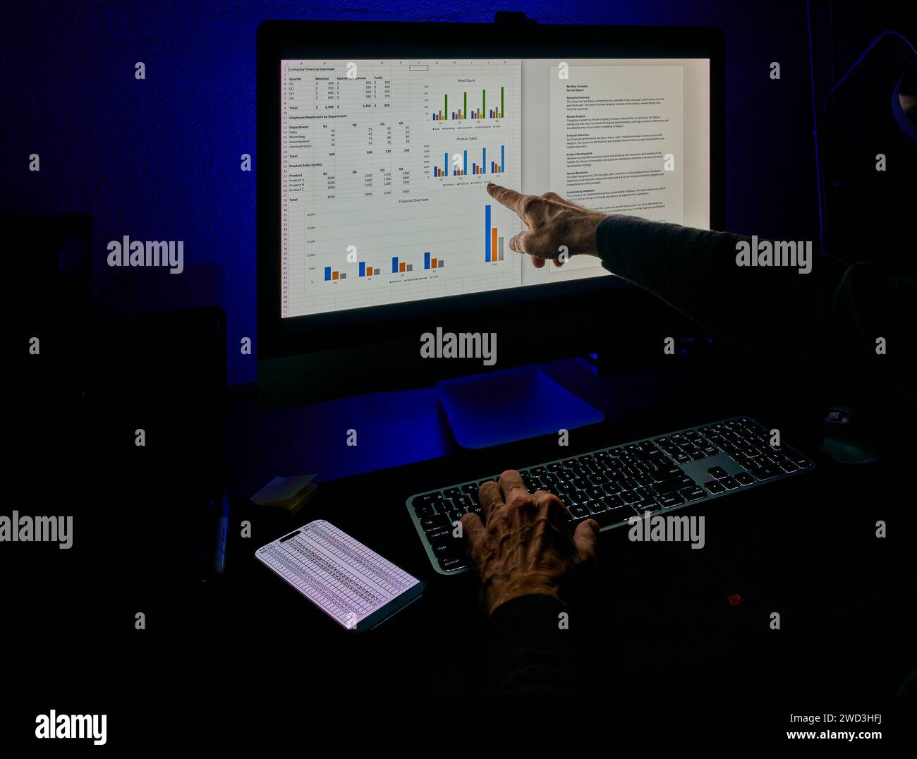 Un professionnel pointe des graphiques financiers sur un moniteur, analysant et discutant des données. Banque D'Images