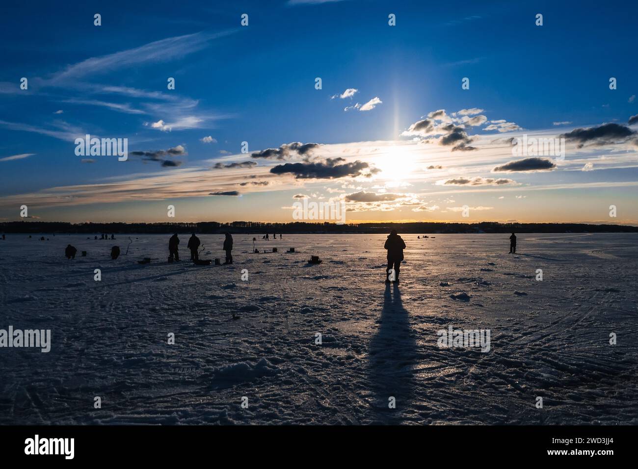 silhouettes de pêcheurs pêchant et vis à glace en hiver sur le lac au lever du soleil le matin Banque D'Images