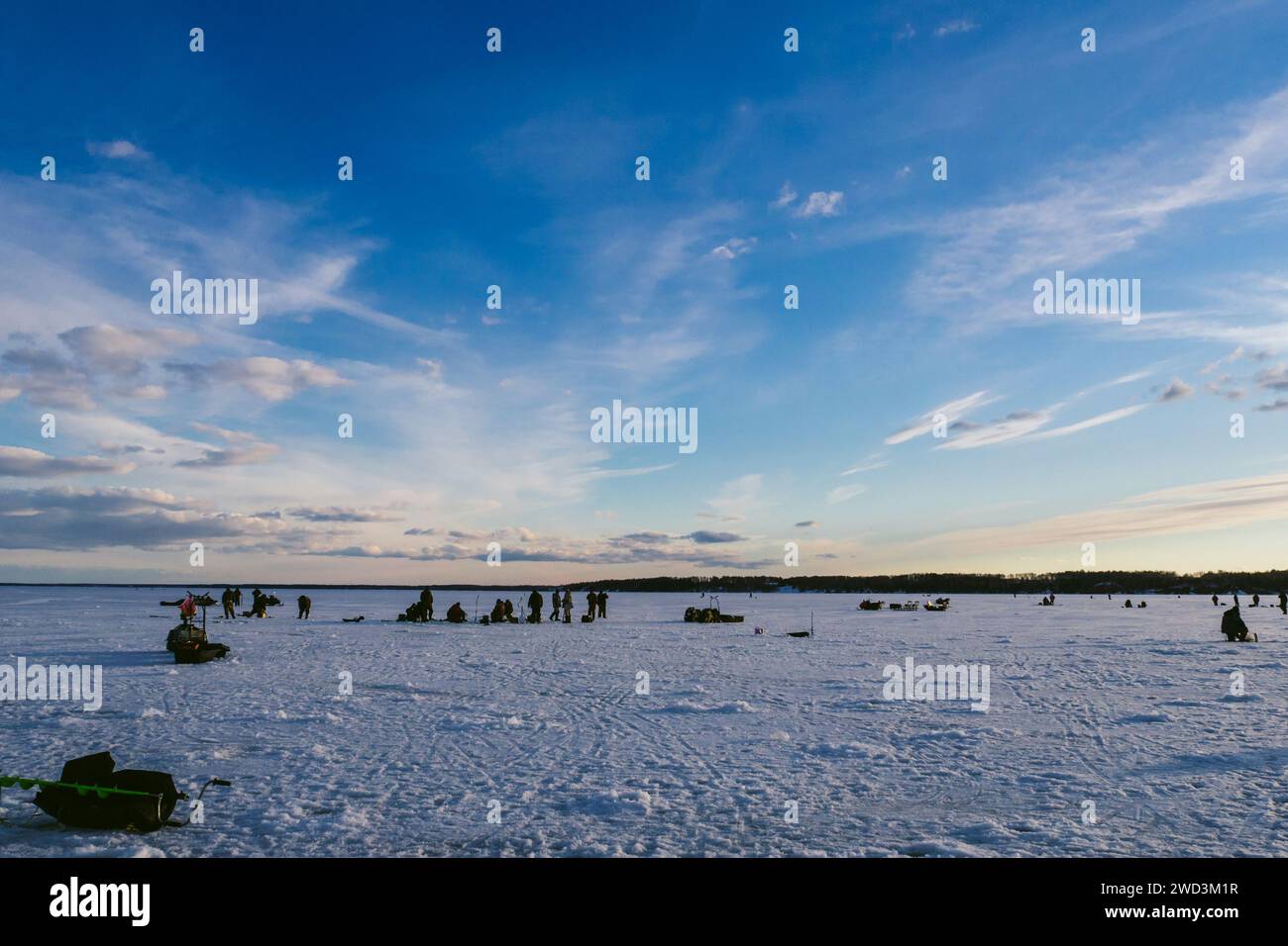 Groupe de pêcheurs pêchant en hiver sur la glace de la rivière au début du matin glacial ensoleillé Banque D'Images