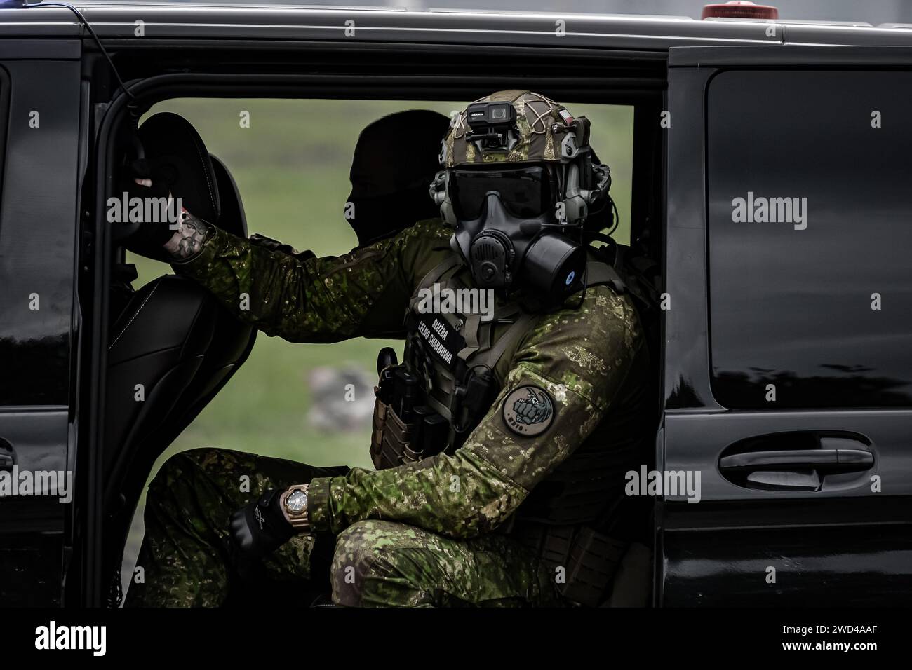 Soldat des forces spéciales dans une camionnette Mercedes noire. Uniforme tactique porté par les forces frontalières tchèques. Homme en masque à gaz Banque D'Images