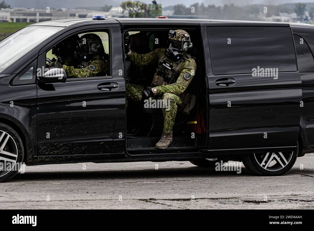 Soldat des forces spéciales dans une camionnette Mercedes noire. Uniforme tactique porté par les forces frontalières tchèques. Homme en masque à gaz Banque D'Images