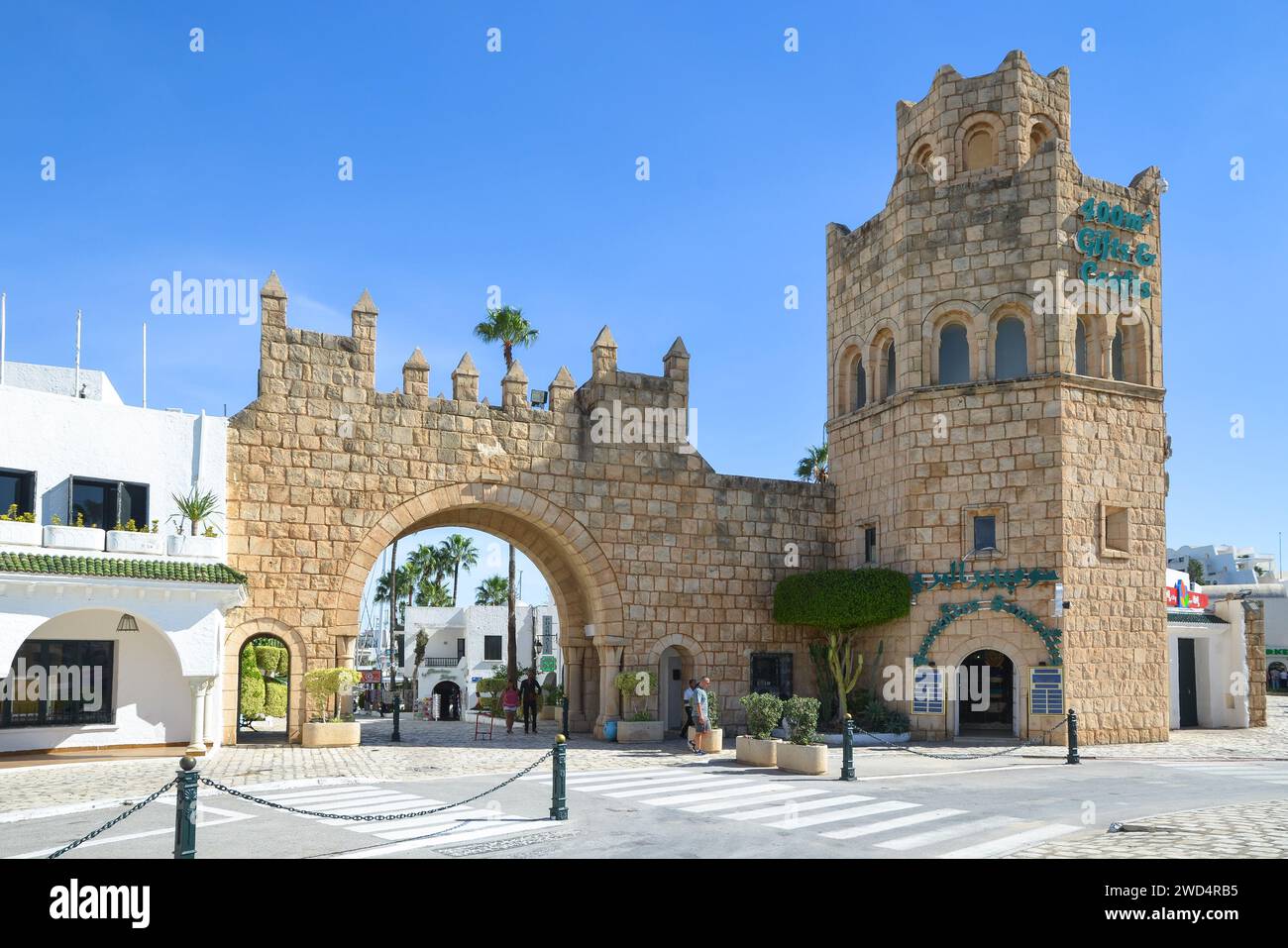 Port El Kantaoui, Sousse, Tunisie. Le portail en pierre et la tour décorent l'entrée de la rue commerçante et de la marina. Banque D'Images