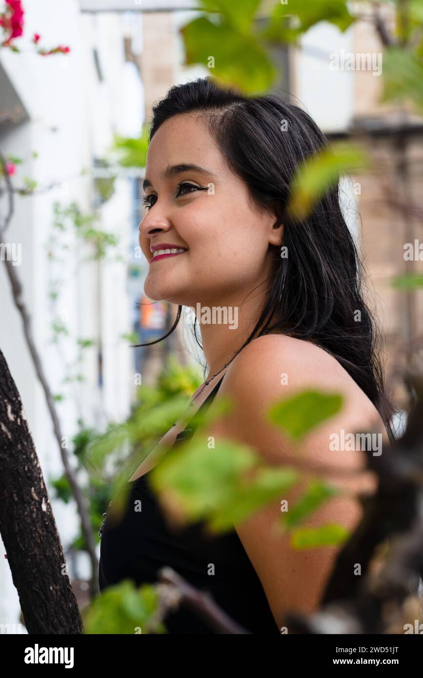 Portrait de belle femme, avec de longs cheveux noirs, à l'extérieur entre les branches et les feuilles. Personne heureuse voyageant. Banque D'Images