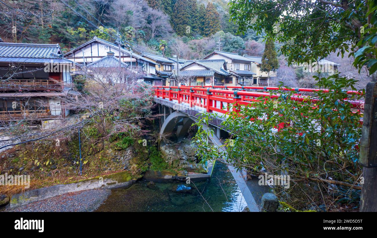 Pont rouge au-dessus de la petite rivière par le village traditionnel japonais Banque D'Images