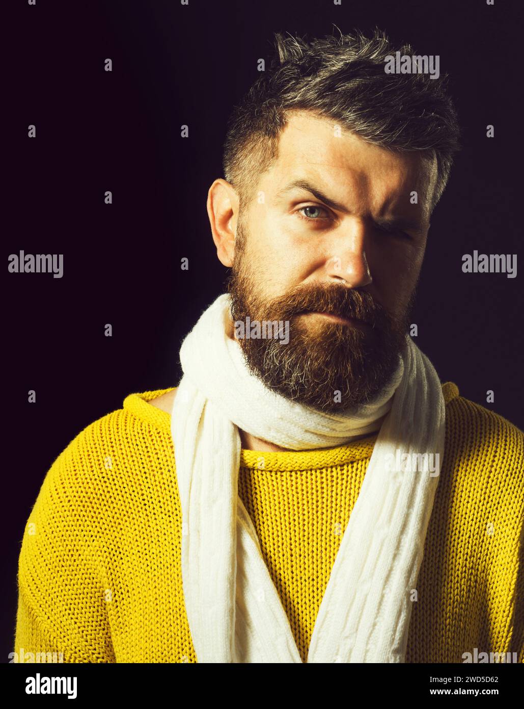 Bel homme barbu en pull d'hiver jaune décontracté et écharpe tricotée blanche. Vêtements automne-hiver. Mode masculin. Portrait en gros plan de attrayant Banque D'Images