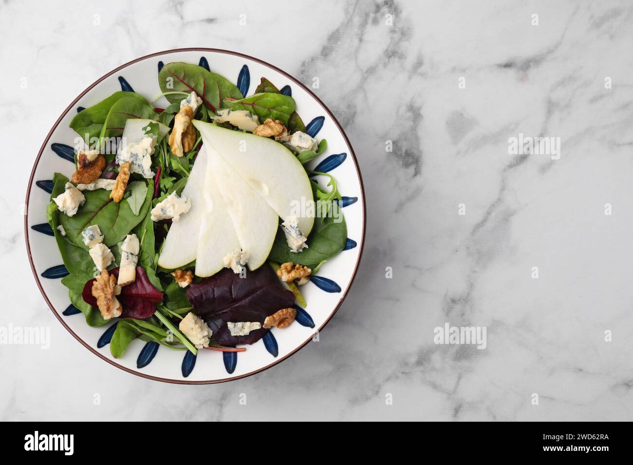 Délicieuse salade de poires dans un bol sur une table en marbre blanc, vue de dessus. Espace pour le texte Banque D'Images