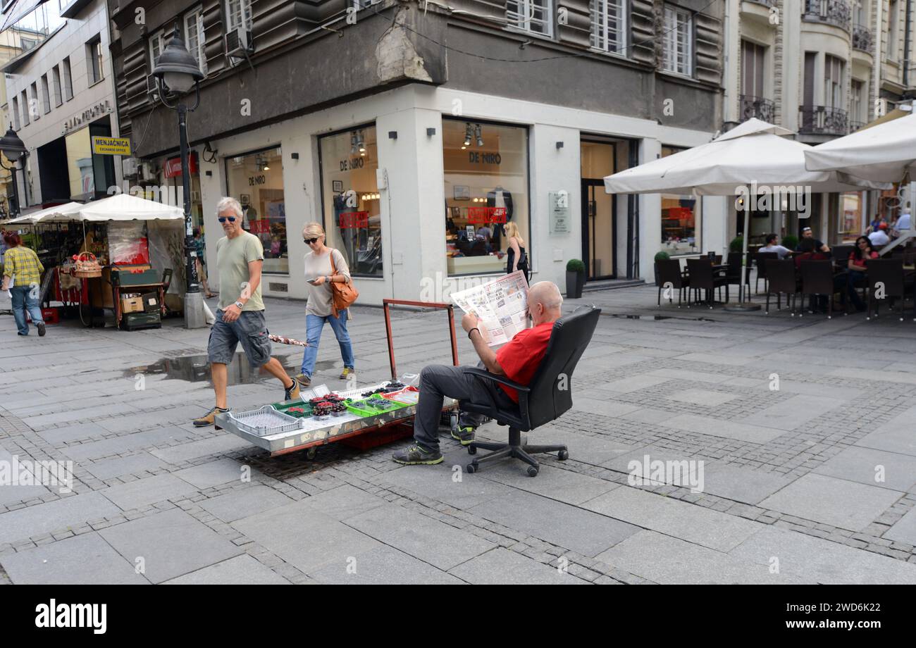 Un vendeur serbe de fruits lisant le journal dans le centre-ville de Belgrade, en Serbie. Banque D'Images