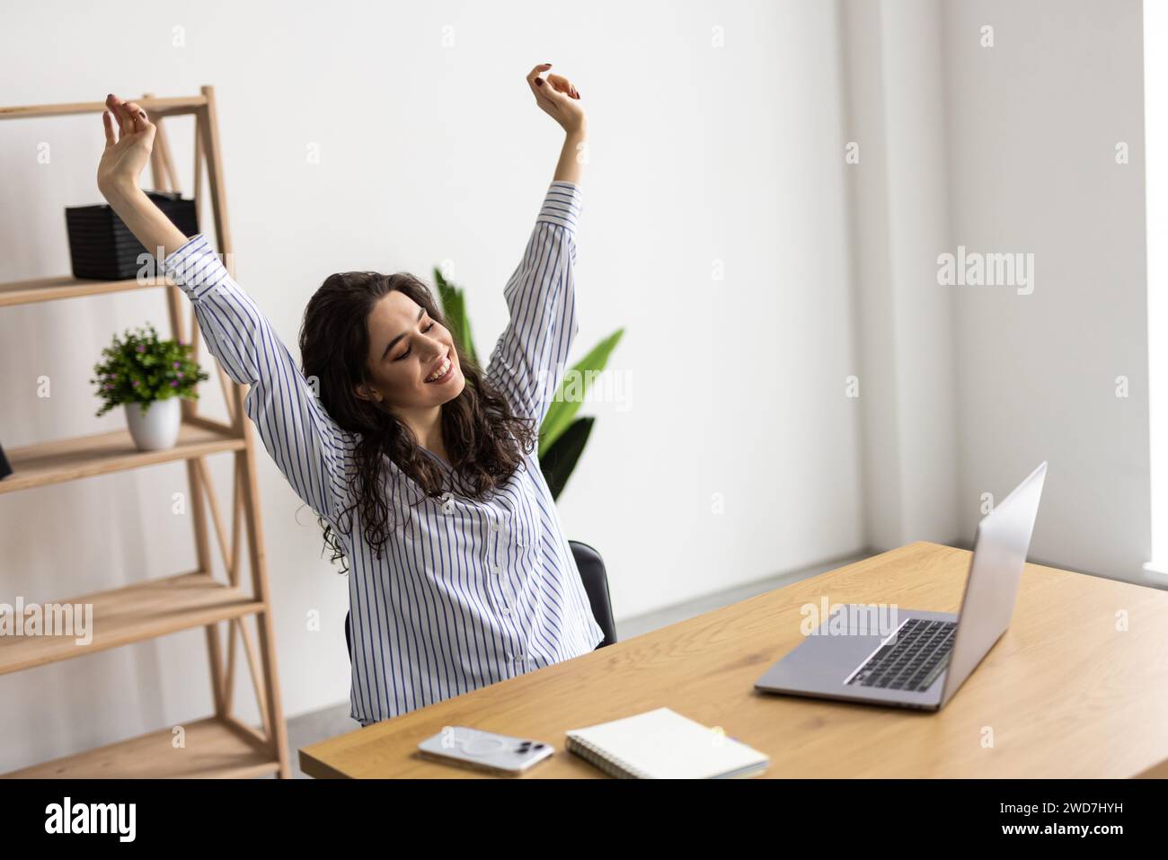 Femme excitée à la maison de travail triomphant avec les mains levées Banque D'Images