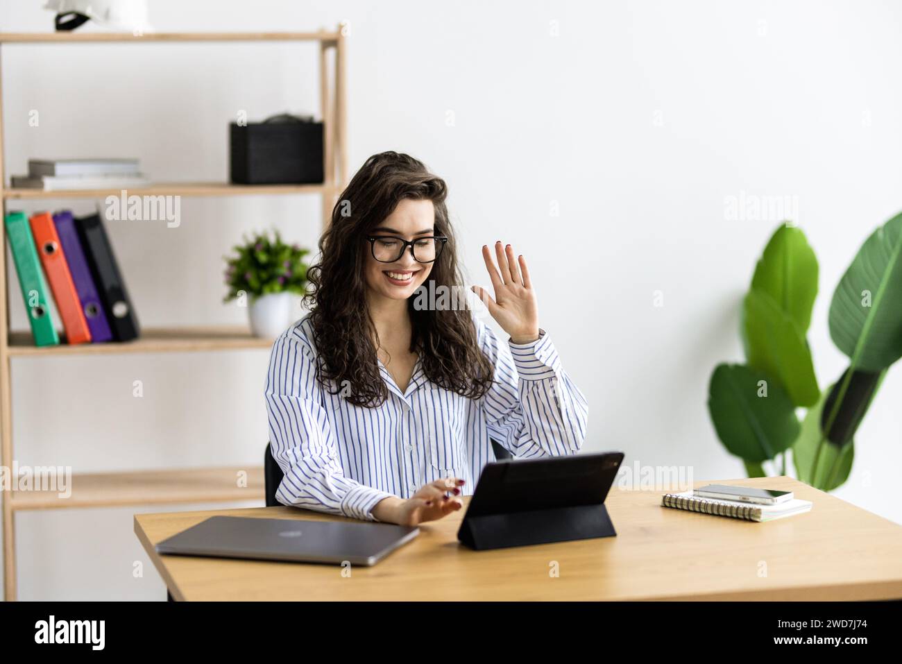 Professionnels office worker waving dans une vidéo conférence avec une tablette sur un bureau Banque D'Images