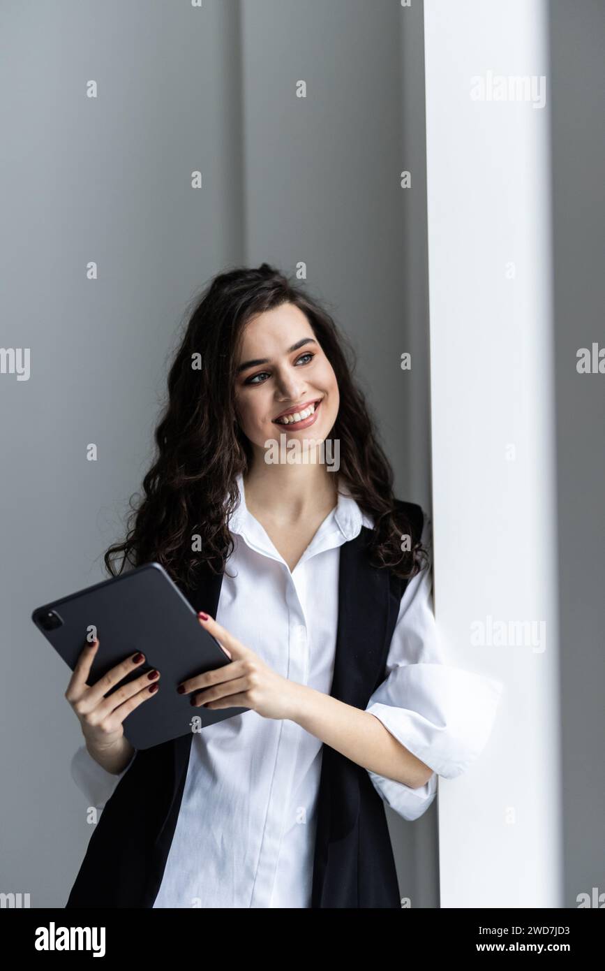 Jeune femme d'affaires heureuse travaillant avec une tablette dans un bureau d'entreprise Banque D'Images