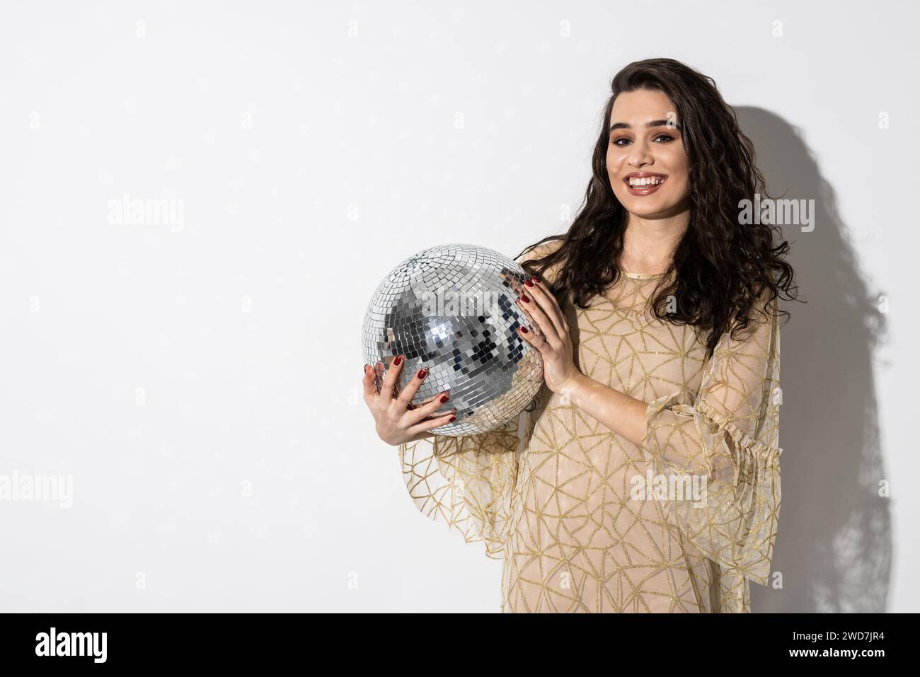 Femme heureuse portant une robe souriante tient une boule disco. Concept de fête Banque D'Images