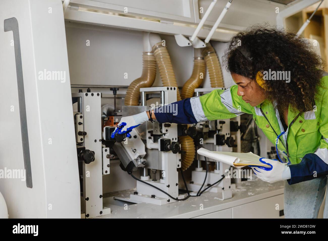 Ingénieur professionnel mécanicien femmes personnel travaillant fixement service de réparation de coupe à bois CNC grande machine dans l'usine de meubles Banque D'Images