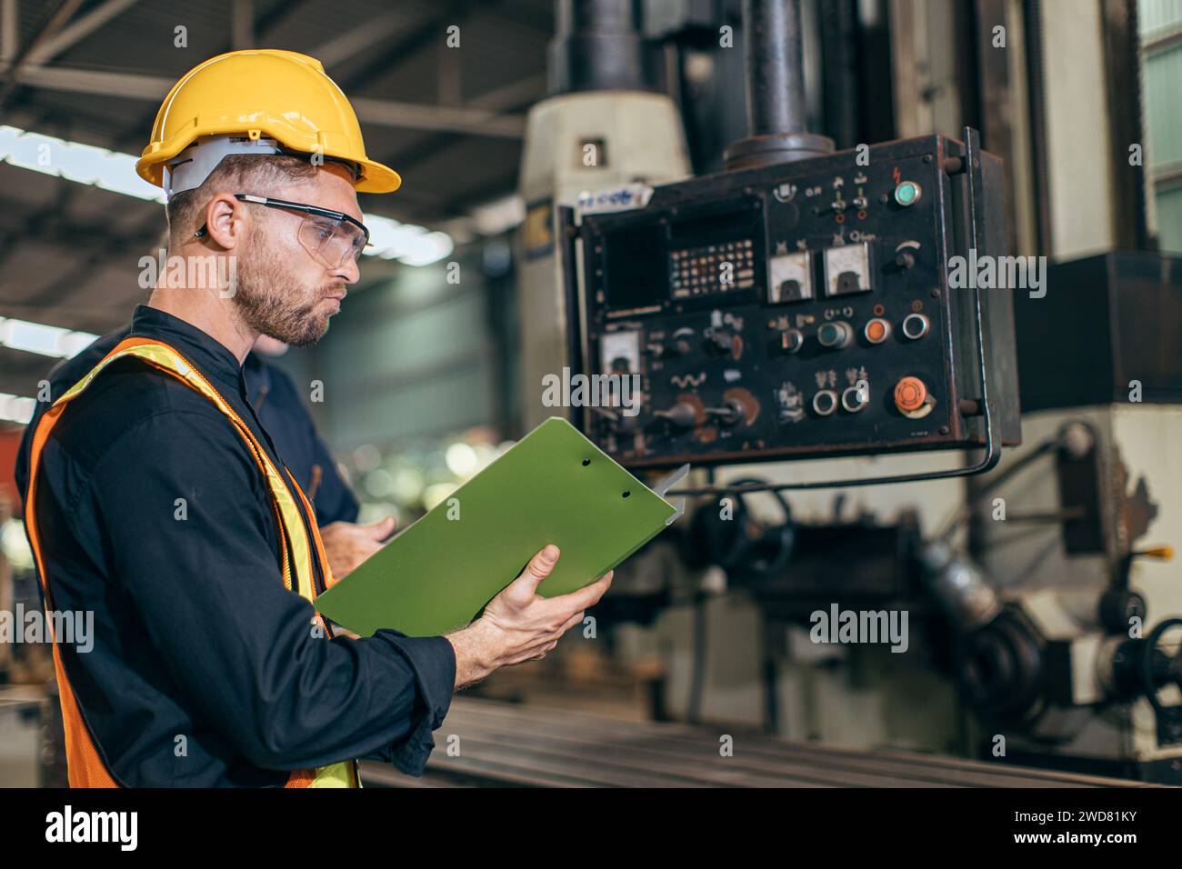 Ingénieur professionnel travaillant la lecture du manuel d'utilisation de commande d'opération de programme CNC fraiseuse dans l'usine d'industrie lourde Banque D'Images
