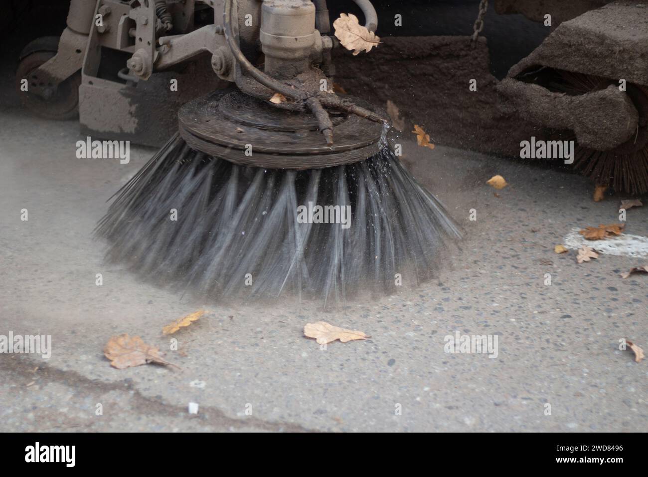 Nettoyage de l'équipement dans la rue. La voiture enlève les feuilles de la route. La brosse nettoie la route. Equipement spécial pour le nettoyage. Banque D'Images