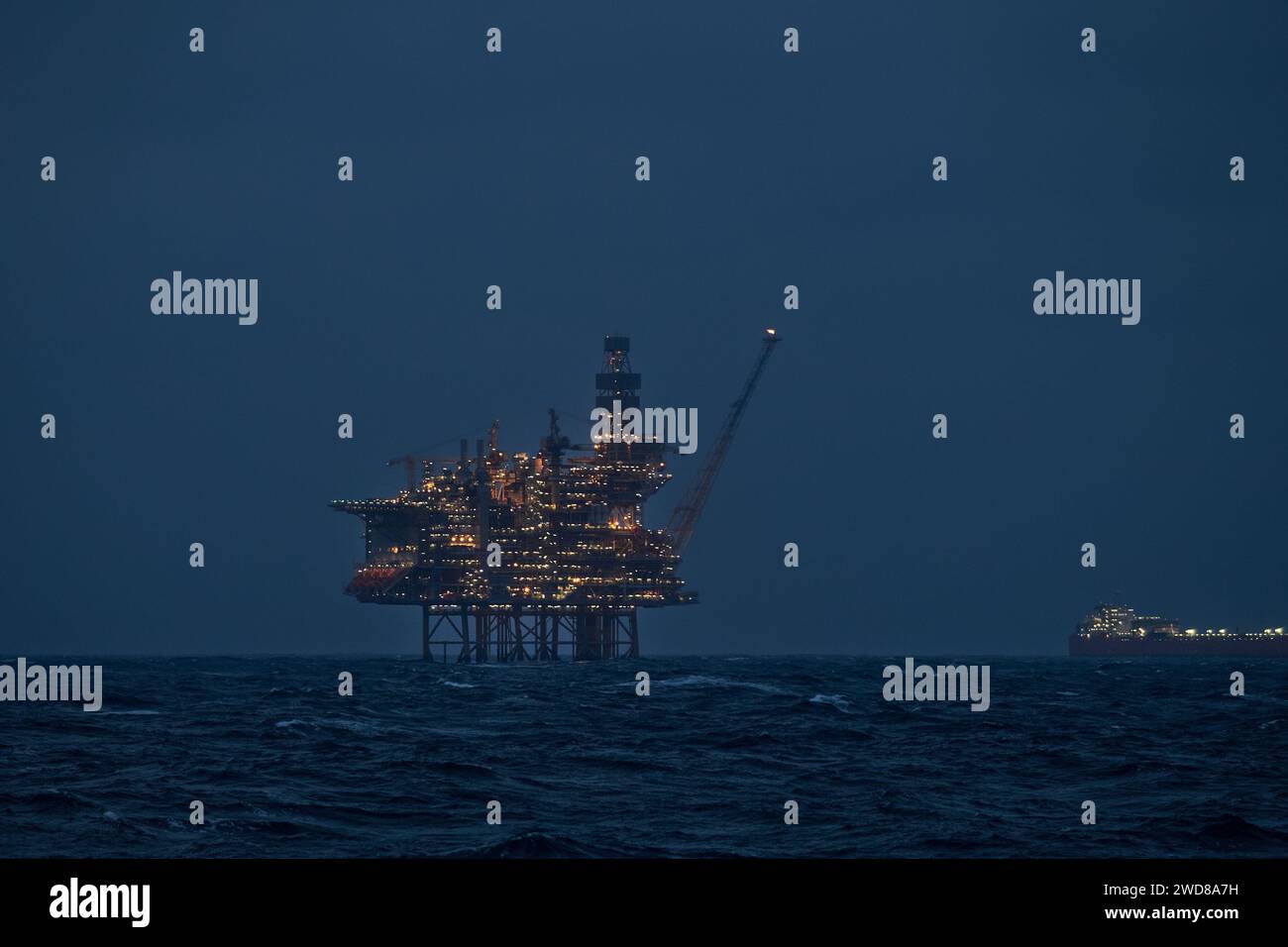 Vue rapprochée de l'engin de forage éclairé et du pétrolier flottant de stockage de production la nuit dans l'océan. Banque D'Images