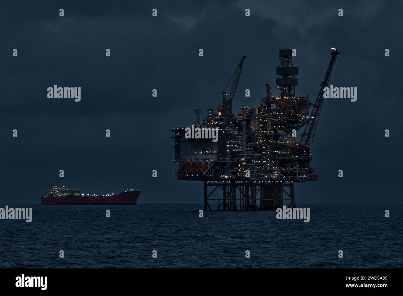 Vue rapprochée de l'engin de forage éclairé et du pétrolier flottant de stockage de production la nuit dans l'océan. Banque D'Images