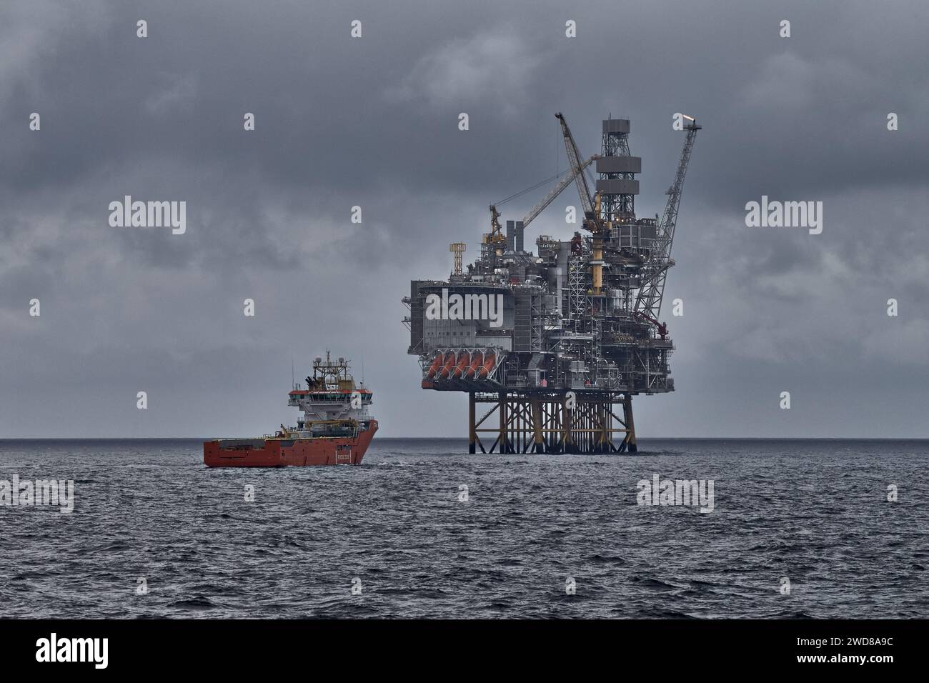 Plate-forme pétrolière et gazière offshore avec navire ravitailleur effectuant des opérations de fret en mer, avec un paysage marin gris spectaculaire. Banque D'Images