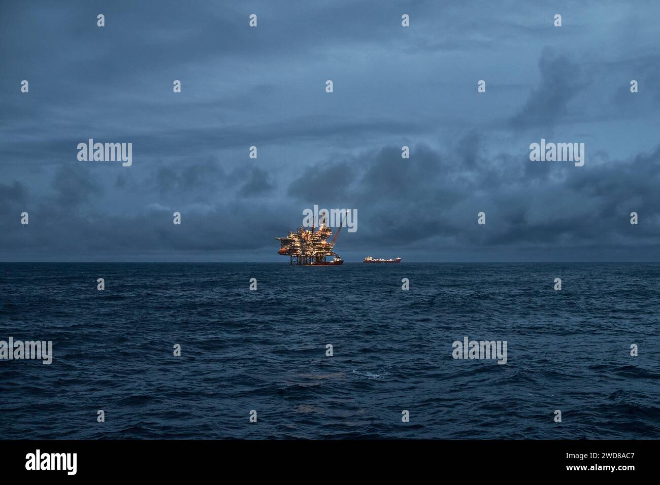 Vue panoramique du pétrole offshore déposé dans la mer, tôt le matin, avec plate-forme de forage pétrolier et gazier et pétrolier à l'horizon. Banque D'Images