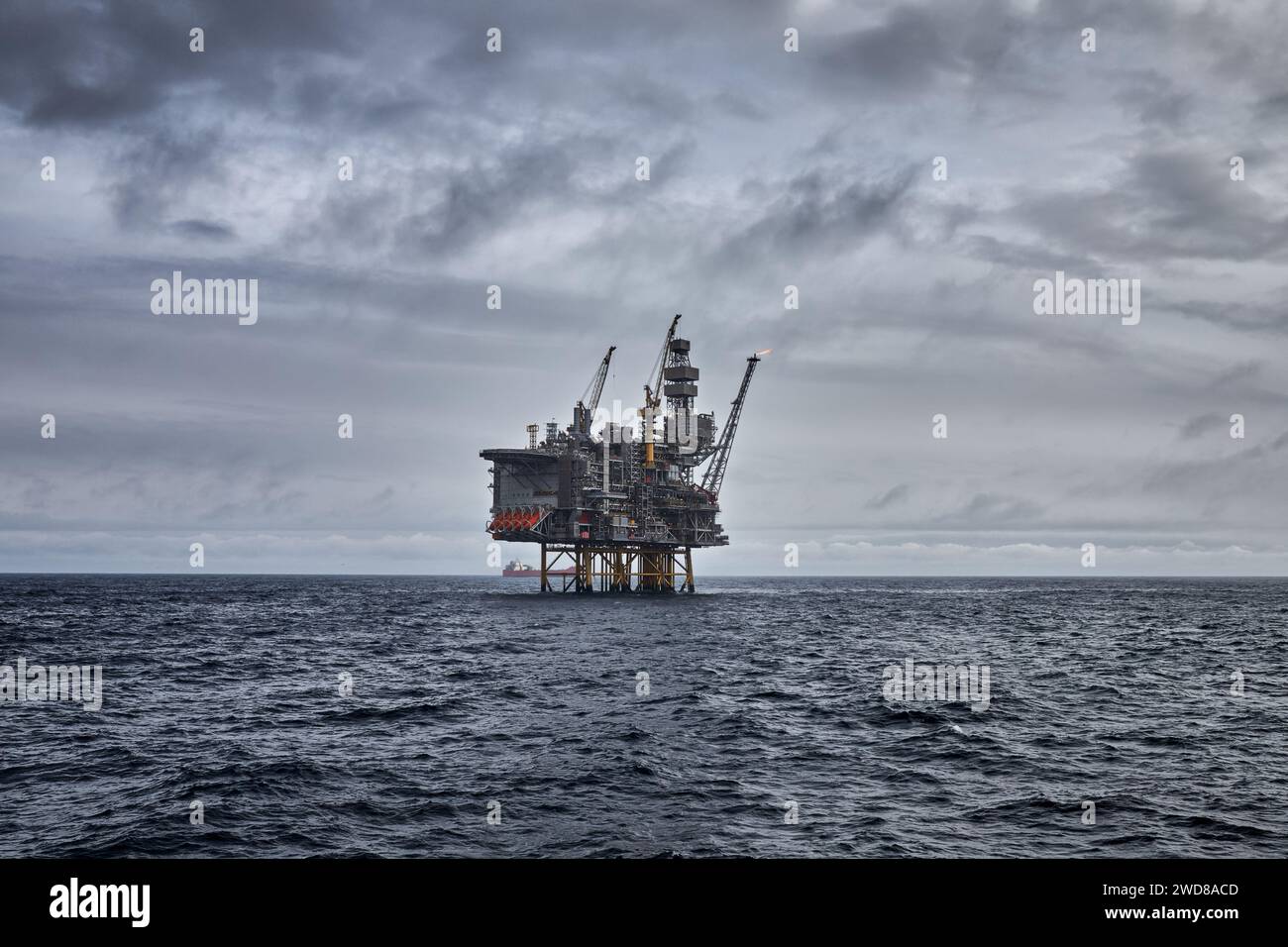 Vue panoramique sur le pétrole offshore et le gazole déposés dans la mer avec une plate-forme de forage à jackup à l'horizon par une journée nuageuse grise. Banque D'Images